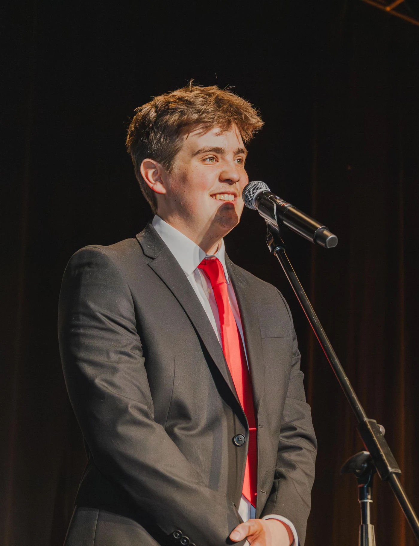 Luke Howe speaking on stage at a microphone